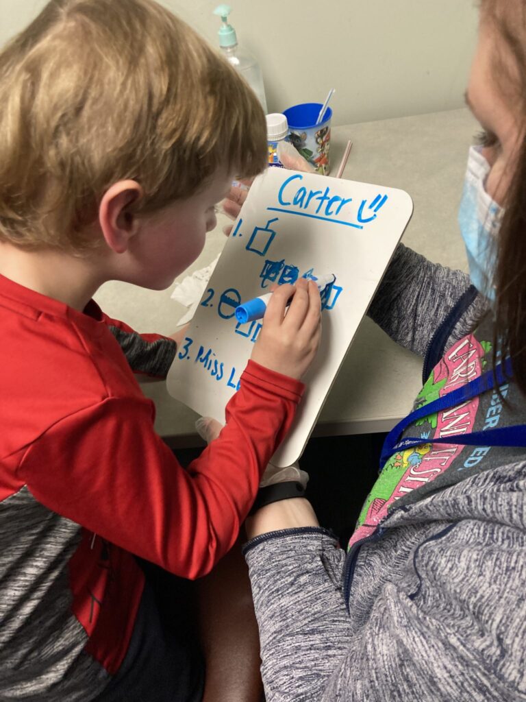 Carter marking off his nutrition goals on a whiteboard with a blue marker.