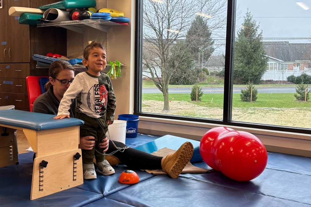 Lucas is standing and smiling while next to a stabilizing block with Laurie behind him.