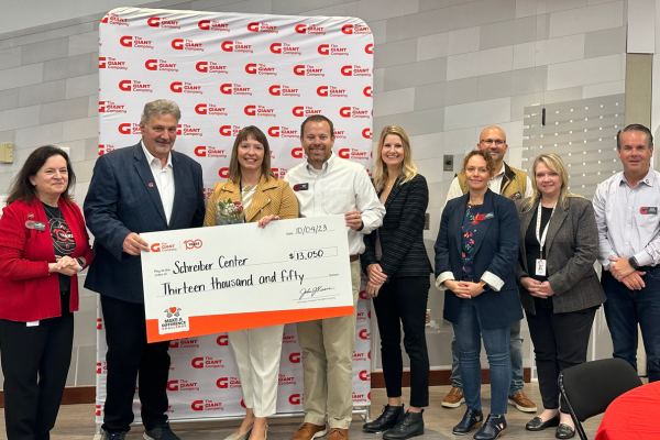 A group of people stand holding an oversized check and smiling.