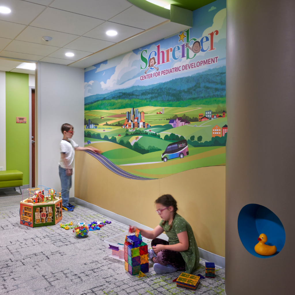 Children playing with toys with Schreiber sign in the background.