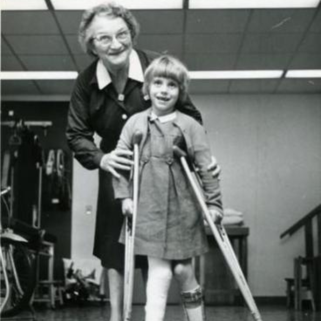 Edna Schreiber and a client, a young child on crutches with their leg in a brace.