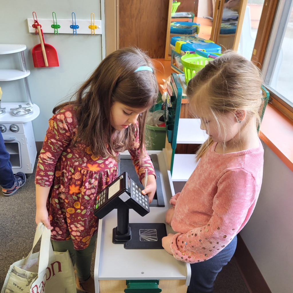 Two children playing with a toy shopping checkout set.