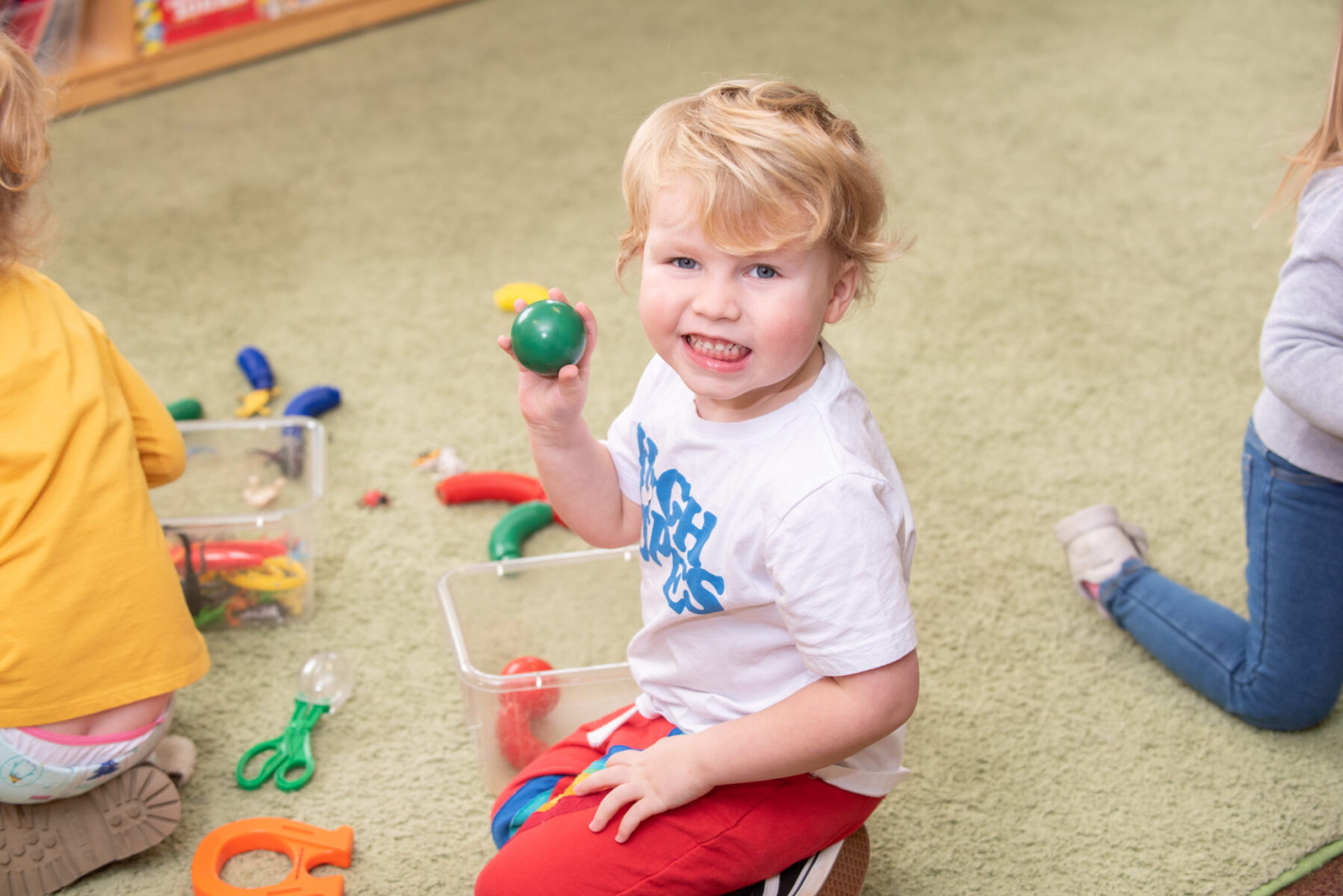 toddler boy showing off his green ball toy