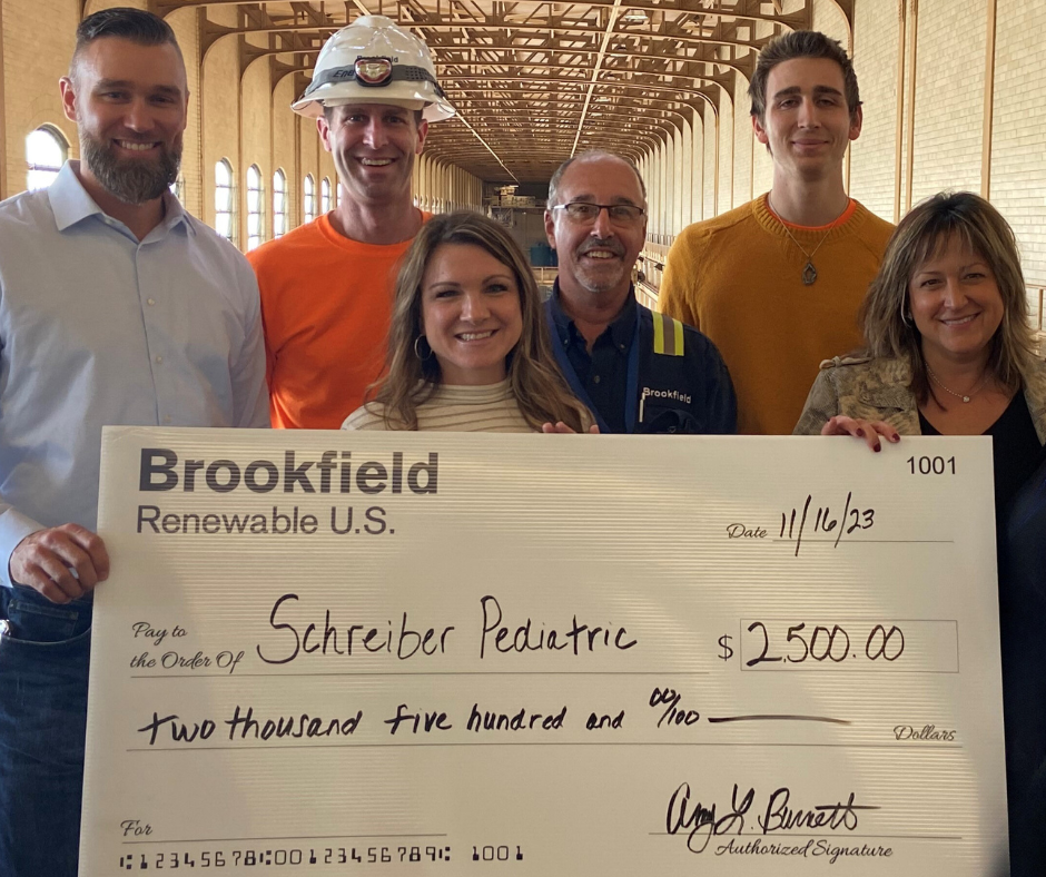 A group of people holding an oversized check made out to Schreiber Pediatric.