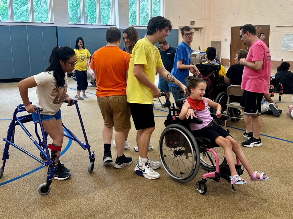 Group of Camp Schreiber attendees in a gymnasium, some using mobility aids.