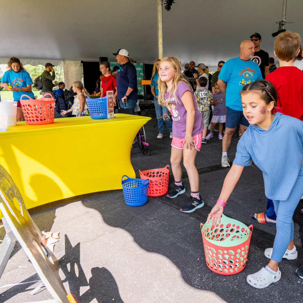 Two children playing bean bag toss at the rubber duckie event.