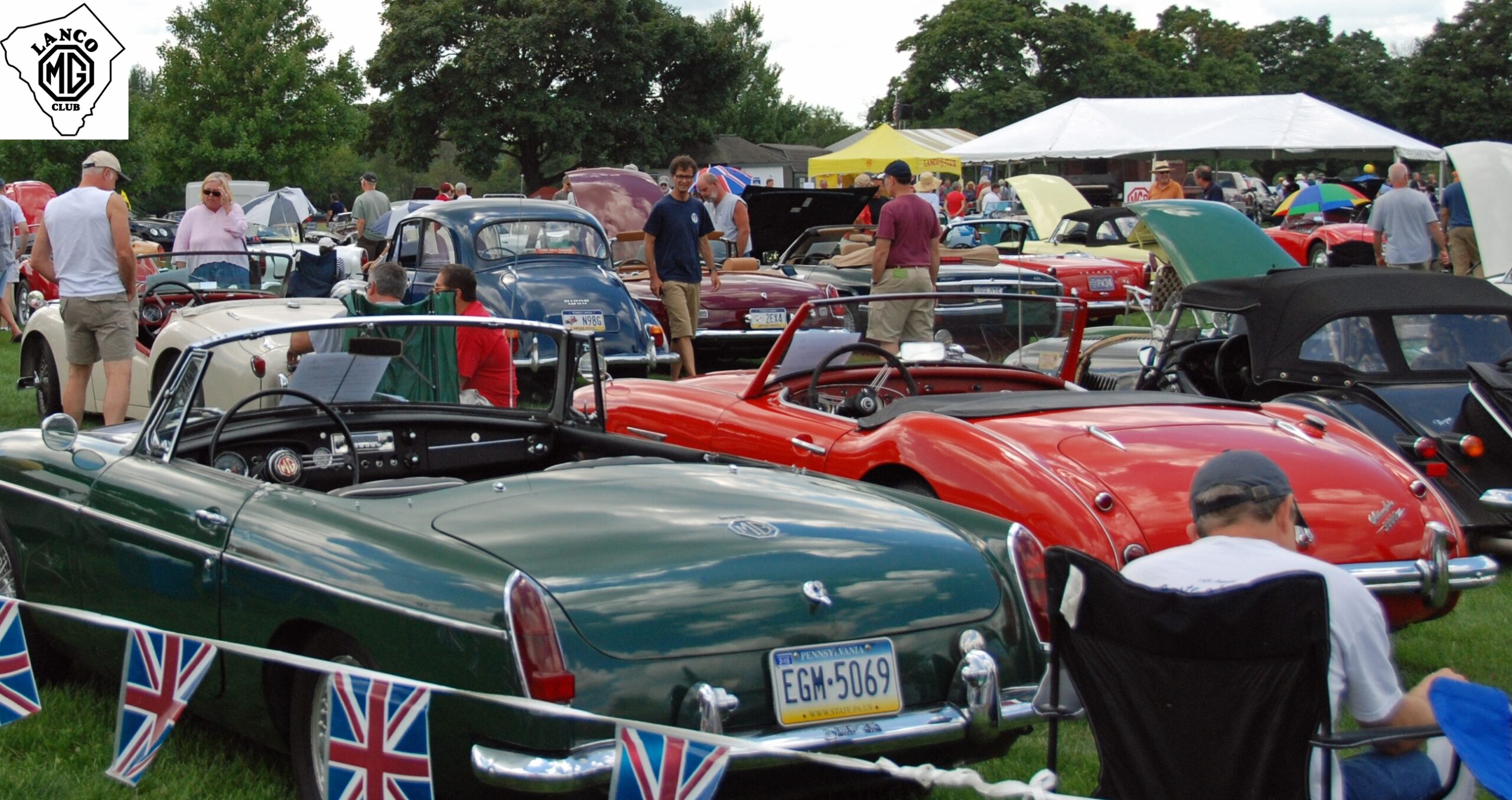 people walking around outside admiring british cars