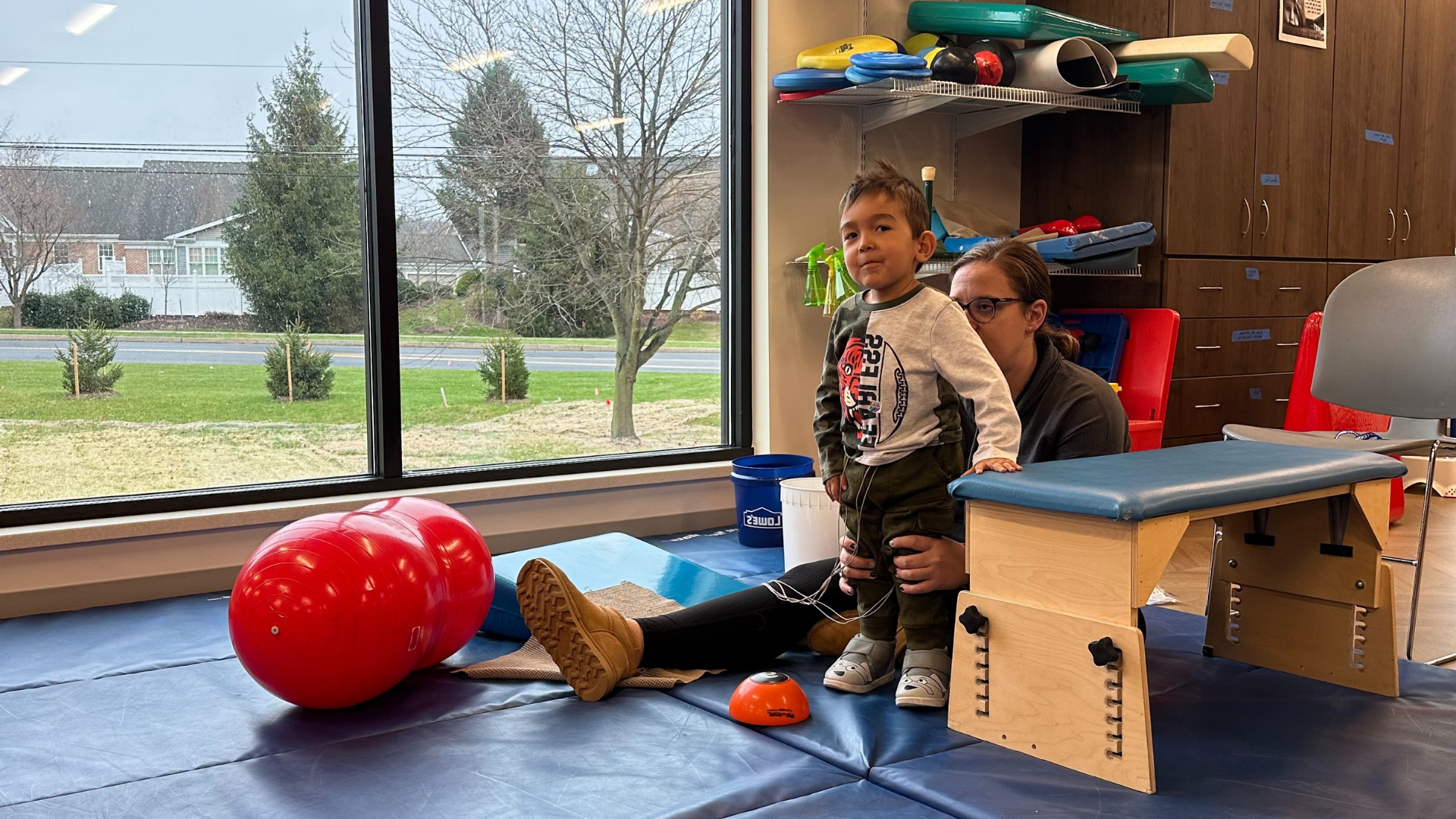 Lucas is standing and smiling while next to a stabilizing block with Laurie behind him.