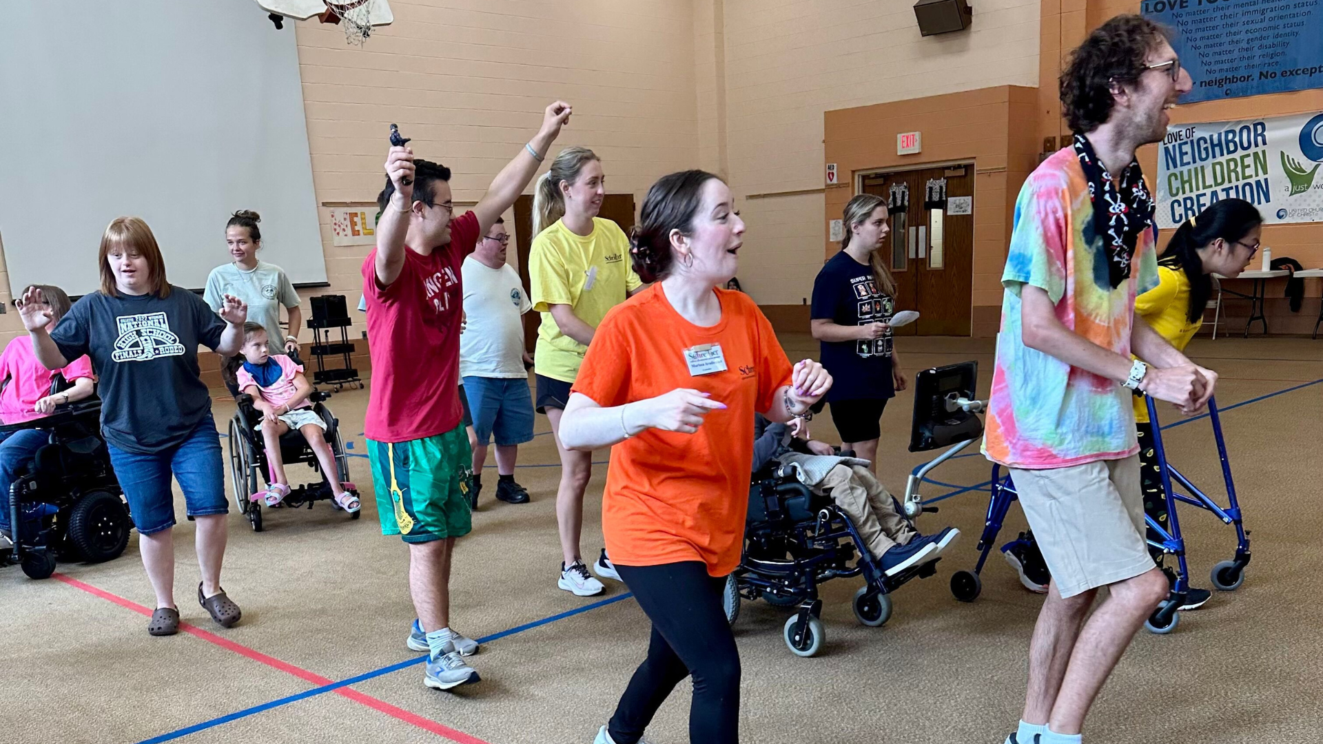 A group of adults and tweens moving around a gymnasium.