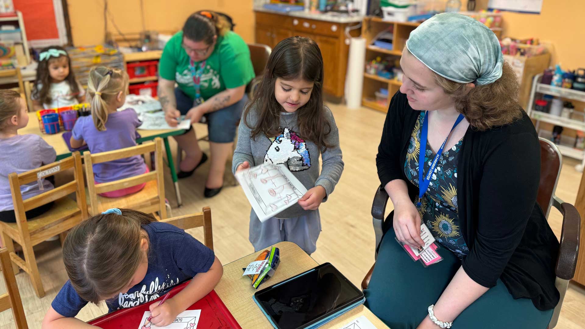 girl in classroom showing off work to teacher