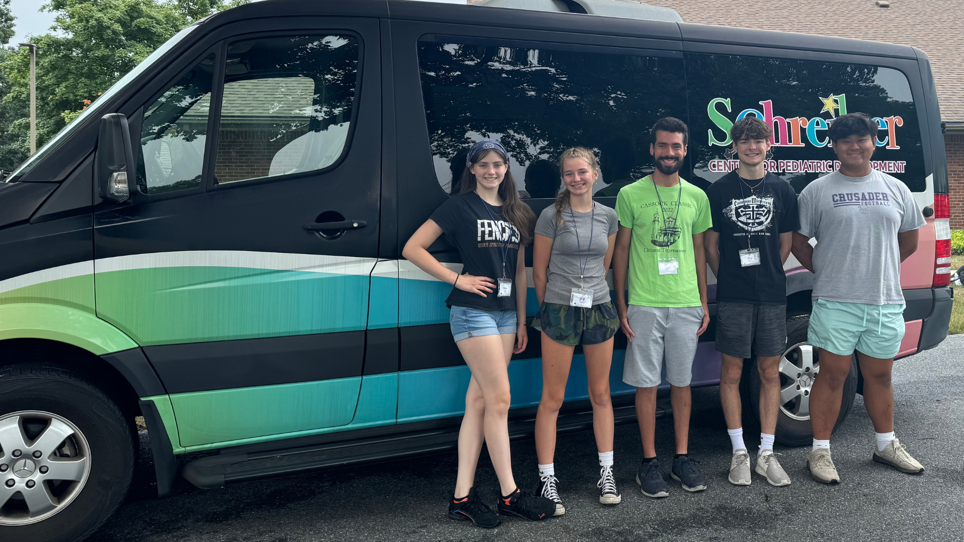 teen volunteers posing in front of van