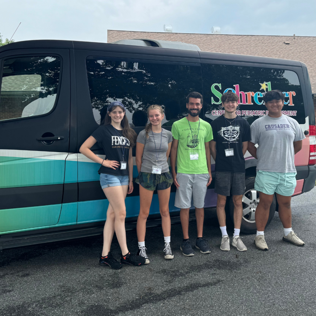 group of young men and women volunteers posing for picture in front of van