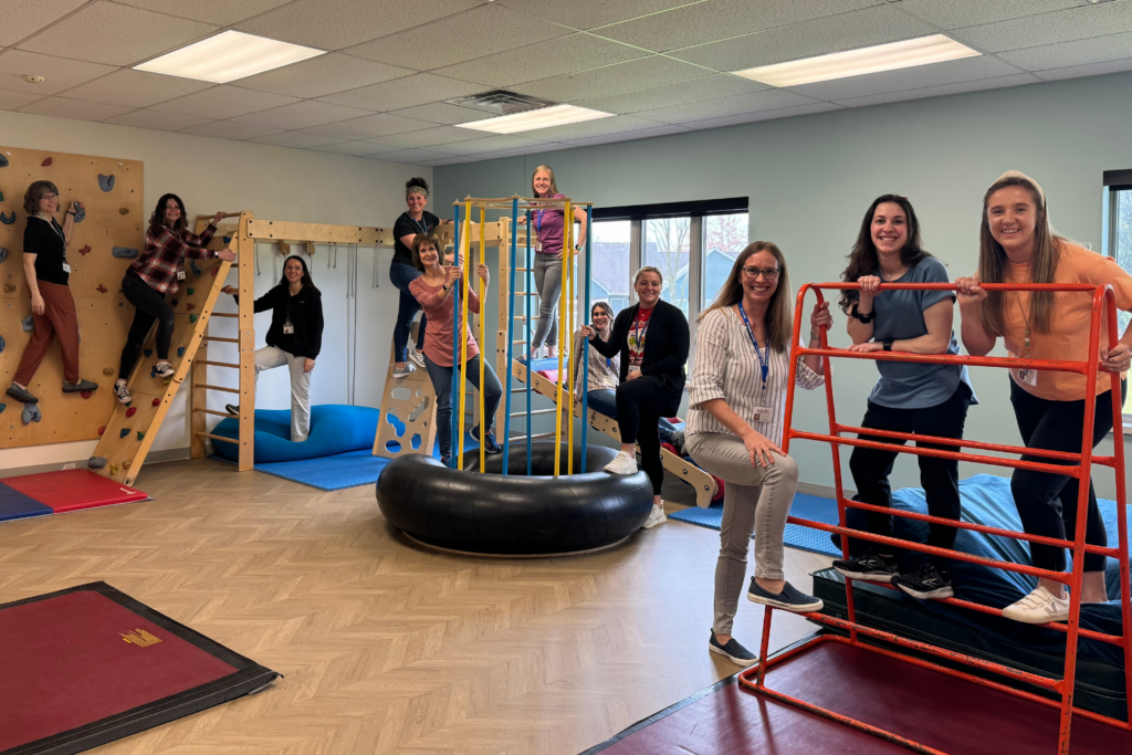 staff and children in gym climbing on equipment and smiling for camera