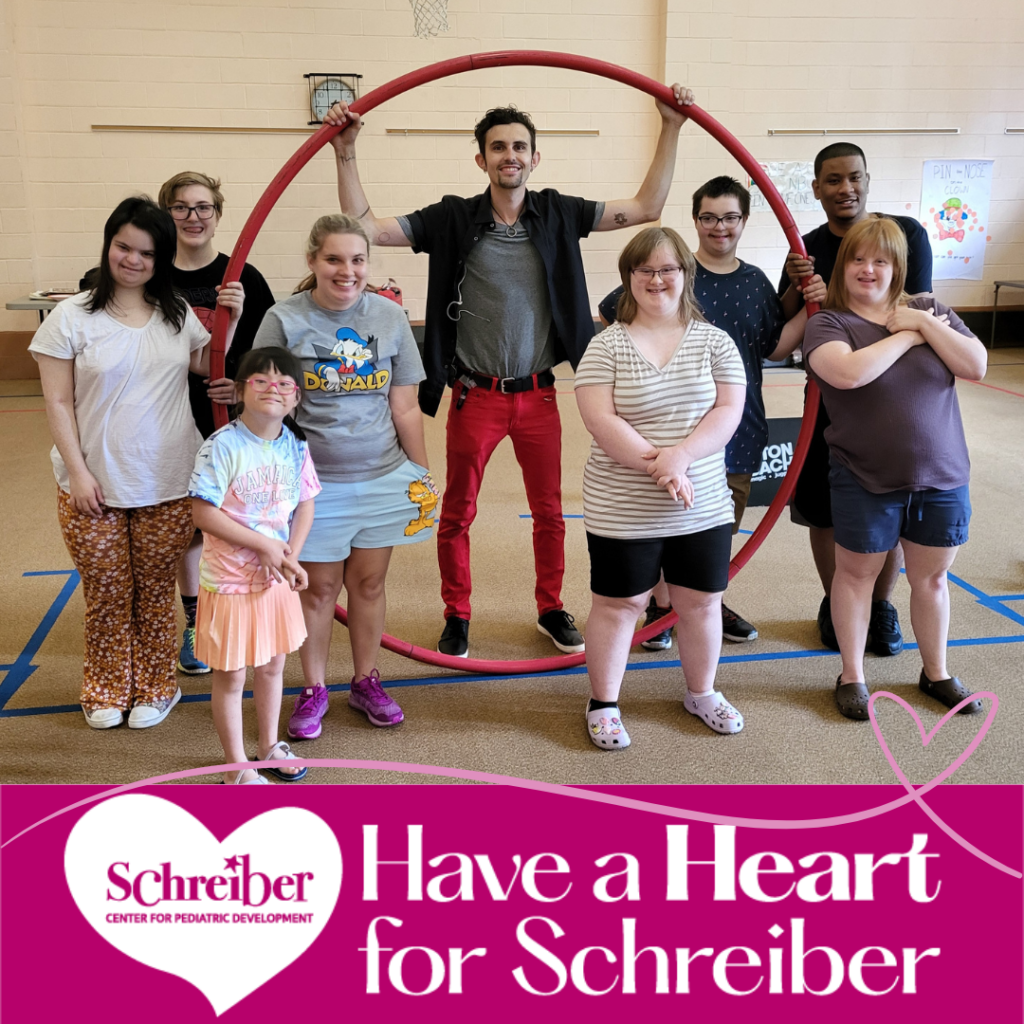 staff and students holding up a large hulu hoop in gym