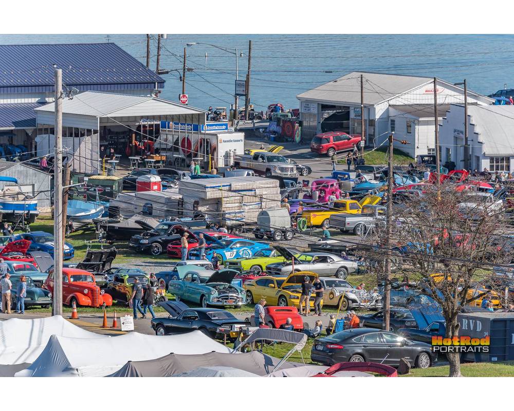 cars in field with tents and garages with the ocean behind venue