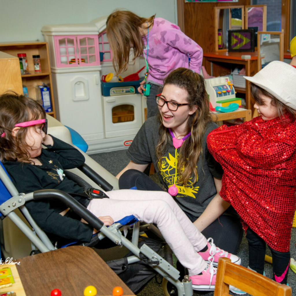 woman and child bent down talking to a little girl in a wheelchair