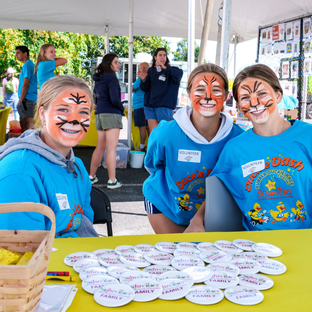 volunteers at duckie event in blue shirts with tiger facepaint