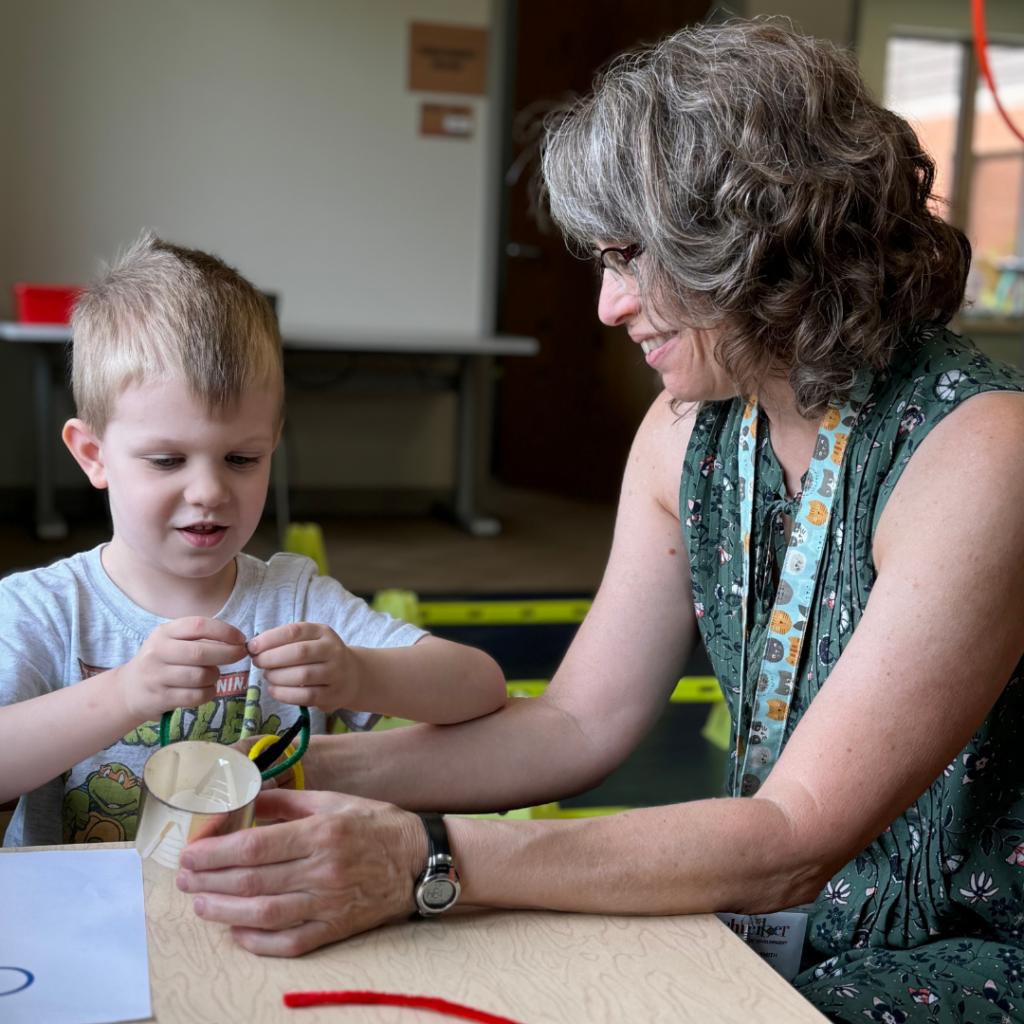 teacher and student working on a project at table