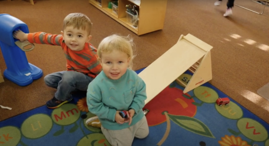 Two preschool age children playing with toys and smiling.