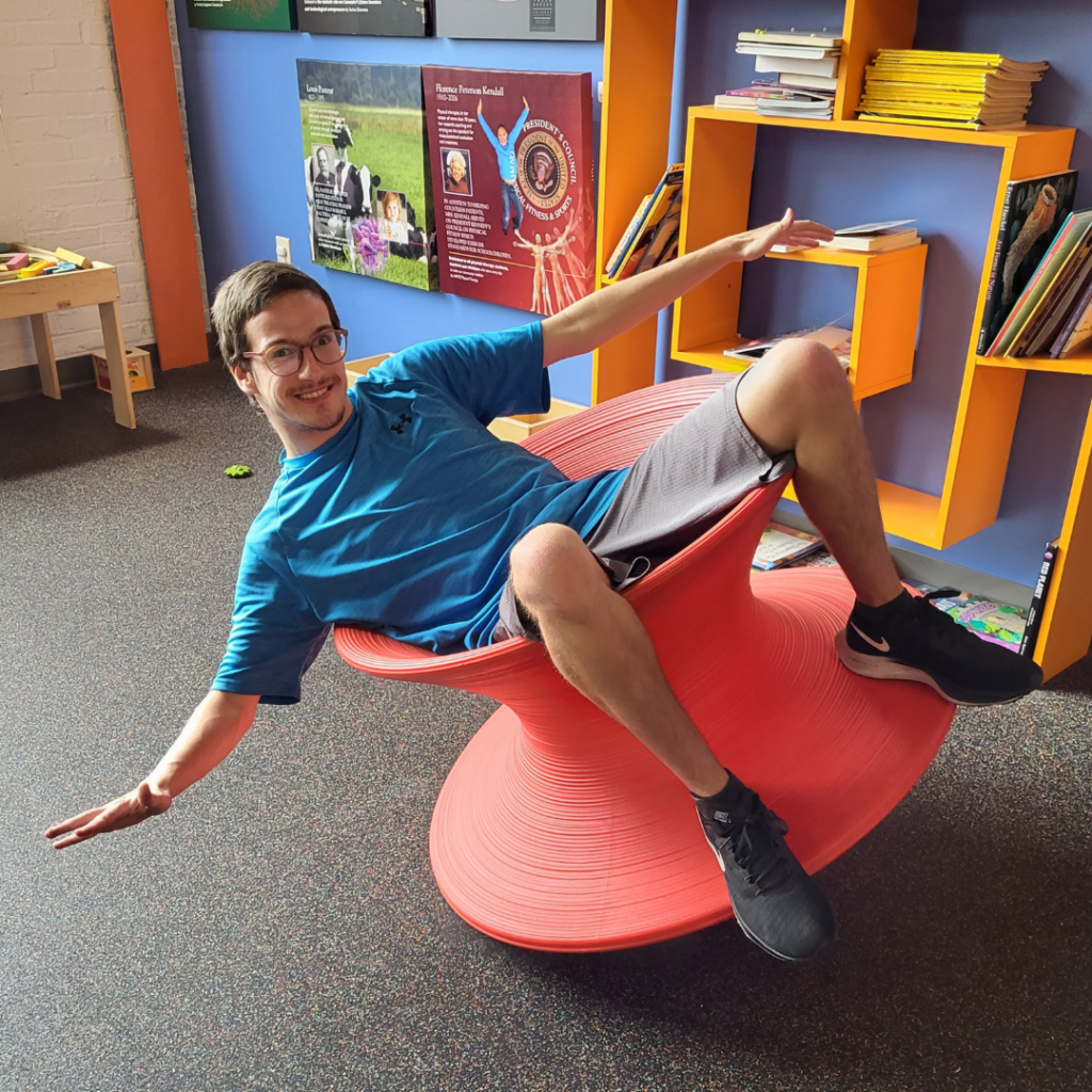 A tween sitting on a red balancing stool.