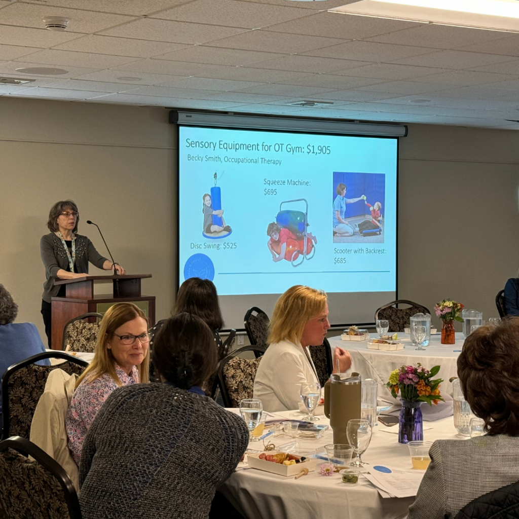 An adult at a podium giving a presentation to a room of people.